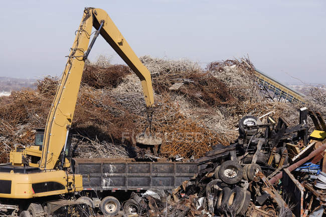 Excavator moving scrap metal with electro magnet in Arlington, Texas — Stock Photo