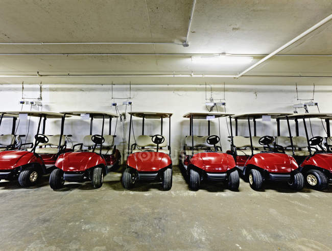 Carros de golf descansando en el interior del garaje de estacionamiento, Bradenton, Florida, EE.UU. - foto de stock