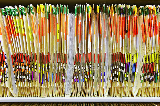 Primer plano de carpetas médicas coloridas en el estante, marco completo - foto de stock