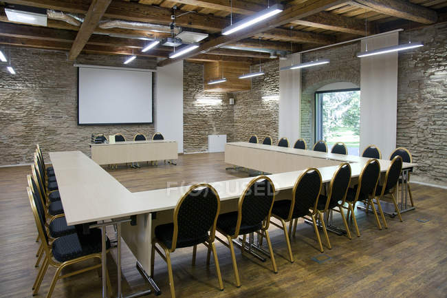 Tavolo a forma di L e schermo di proiezione nella sala conferenze — Foto stock
