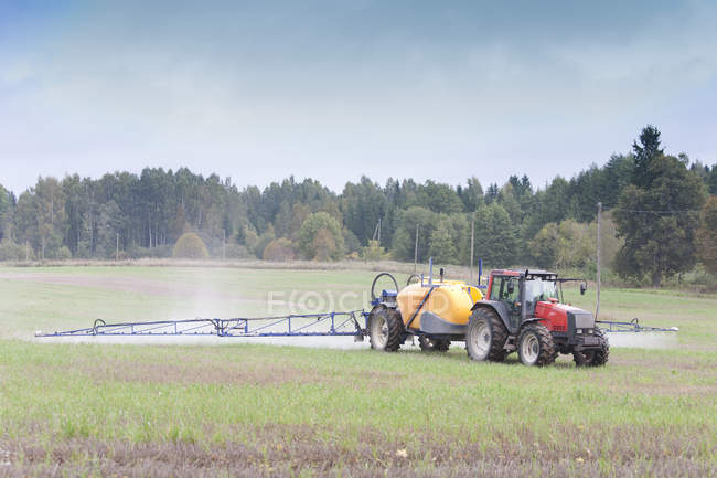 Tractor rociando herbicidas en el campo, Estonia - foto de stock