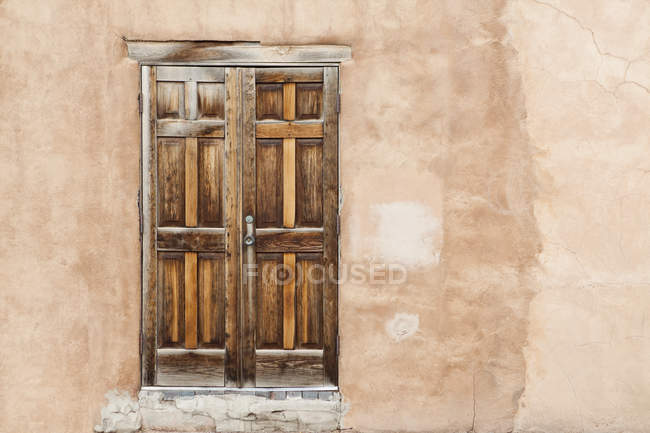Antigua puerta de madera en fachada de adobe envejecido, Santa Fe, Nuevo México, EE.UU. - foto de stock