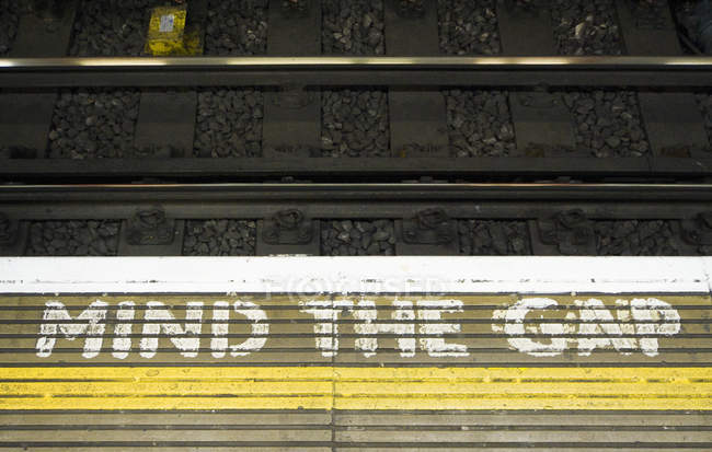 Advertencia del metro en el borde de la plataforma en Londres, Inglaterra, Reino Unido - foto de stock