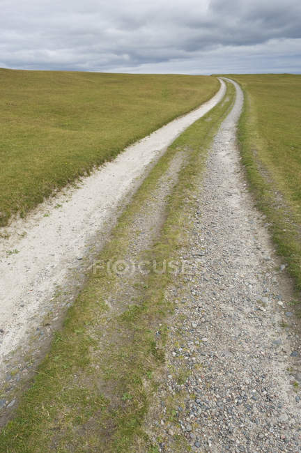 Sentiero sterrato attraverso praterie di campagna sotto il paesaggio nuvoloso, Argyll, Scozia, Regno Unito — Foto stock