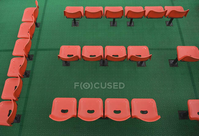 Orange chairs rows on green carpet, high angle view — Stock Photo