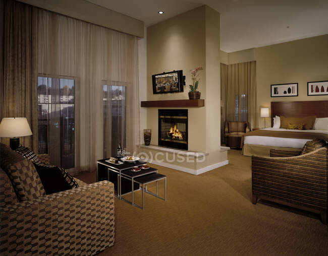 Hotel room with armchairs and tv by fireplace — Stock Photo