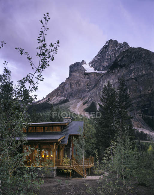 Maison de montagne dans les bois au crépuscule sous le ciel crépusculaire — Photo de stock
