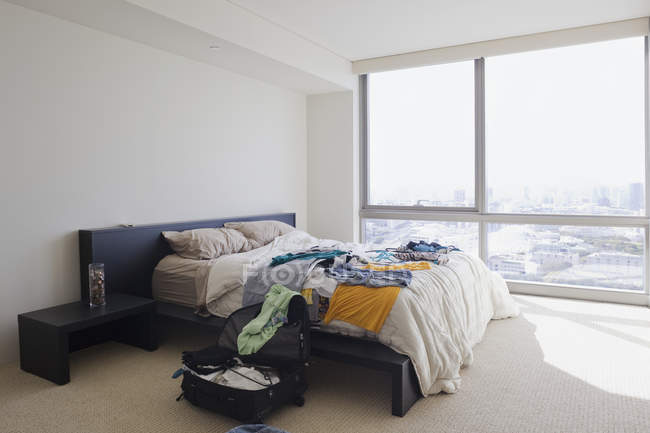 Dormitorio desordenado con ropa en la cama en Honolulu, Hawaii, Estados Unidos - foto de stock