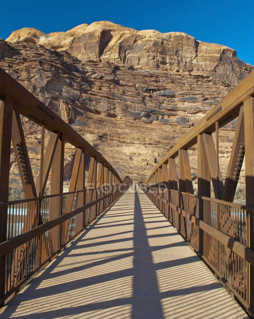 Pedestrian walking bridge with rocky background — Stock Photo