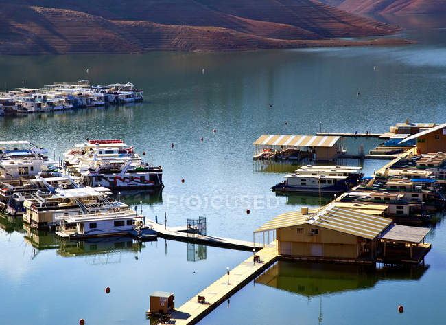 Houseboats and pier in lake in mountains in autumn — Stock Photo
