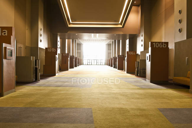 Corredor en centro de conferencias con puertas numeradas y retroiluminadas - foto de stock
