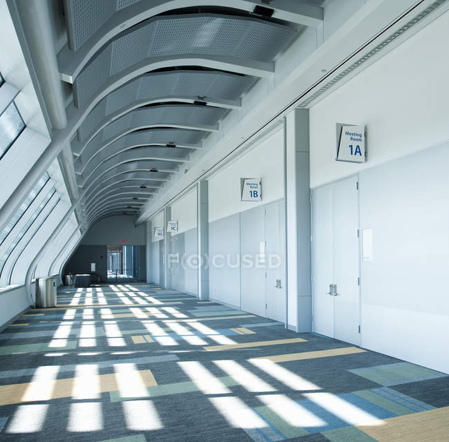 Corridor in conference center with numbered doors and shadow pattern on floor — Stock Photo