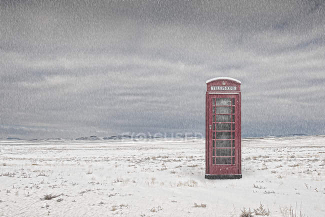 Cabina telefonica nel paesaggio innevato sotto tempesta — Foto stock