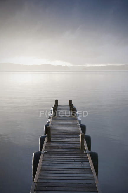Jetée en bois au-dessus du lac brumeux, Taupo, Île du Nord, Nouvelle-Zélande — Photo de stock