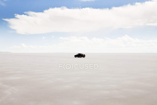 Car driving on white Utah salt flats in USA — Stock Photo