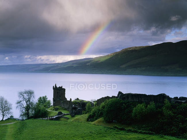 Castillo Urquhart en la orilla del Lago Ness con arco iris sobre el agua, Escocia, Reino Unido - foto de stock
