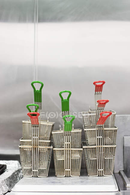 Deep fryer baskets stacked in commercial kitchen — Stock Photo