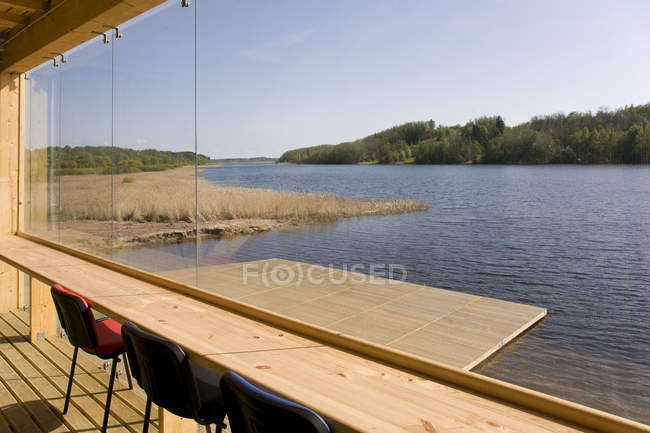 Сільська будівля на березі озера та дерев'яний док через вікно — стокове фото