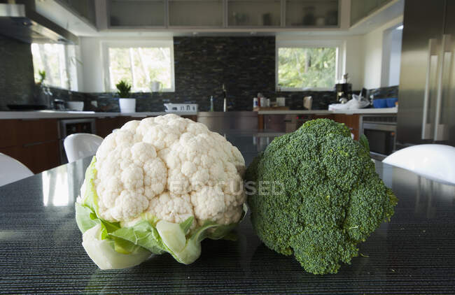Têtes de brocoli et de chou-fleur sur une table dans la cuisine — Photo de stock