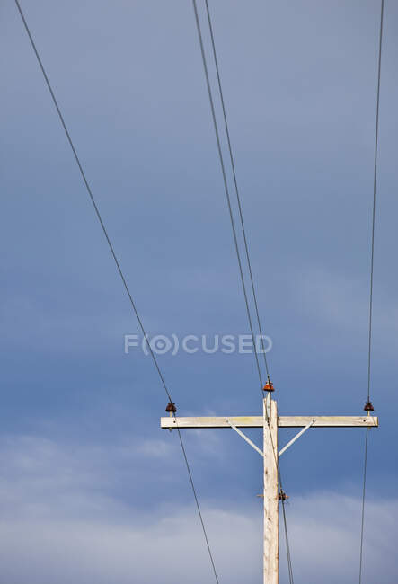 Телефонний полюс з дротами проти блакитного неба — стокове фото