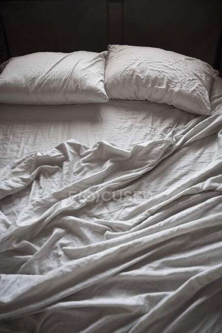 Unmade bed with white sheets, high angle view — Stock Photo