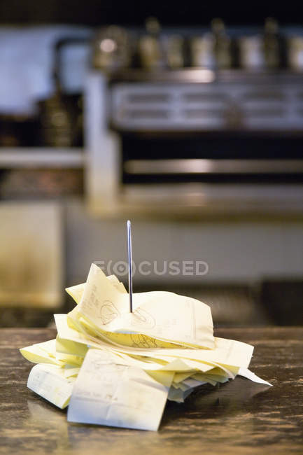 Diner receipts on spindle on wooden table, close-up — Stock Photo