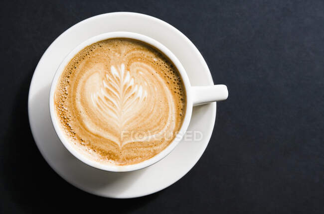 Cup of coffee on black background, top view — Stock Photo