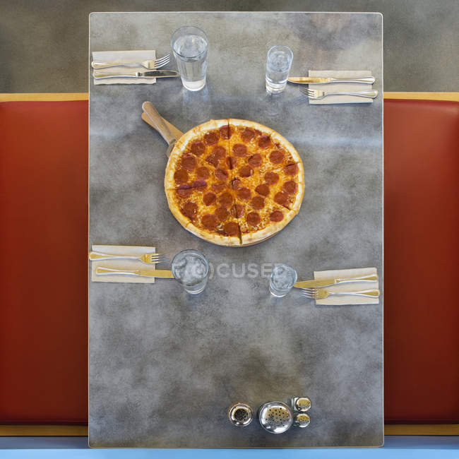 Pizza on served table in restaurant, top view — Stock Photo