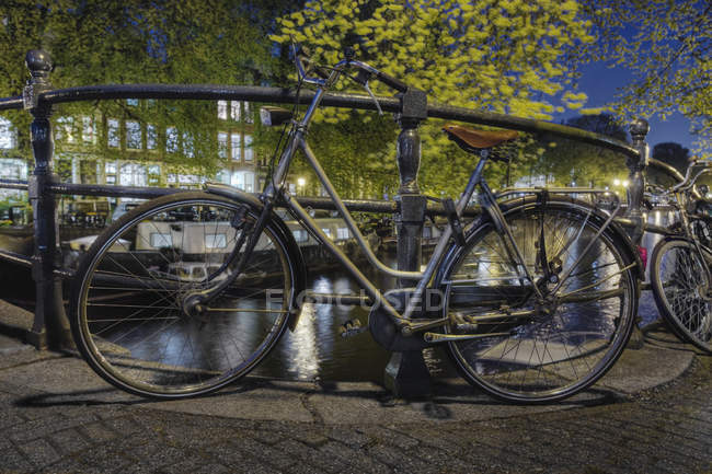 Bicicletas aseguradas a la barandilla del canal en Amsterdam, Países Bajos - foto de stock