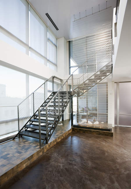 Escaleras de metal que conducen al segundo piso en apartamento moderno - foto de stock