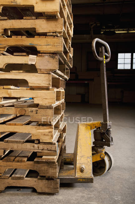 Hand truck and wooden pallets in factory — Stock Photo