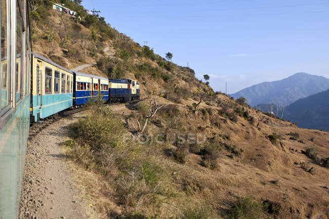 Поезд едет через сельскую местность в Дхарампуре, Химачал-Прадеш, Индия — стоковое фото