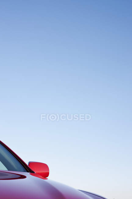 Driver side mirror and hood of red car — Stock Photo