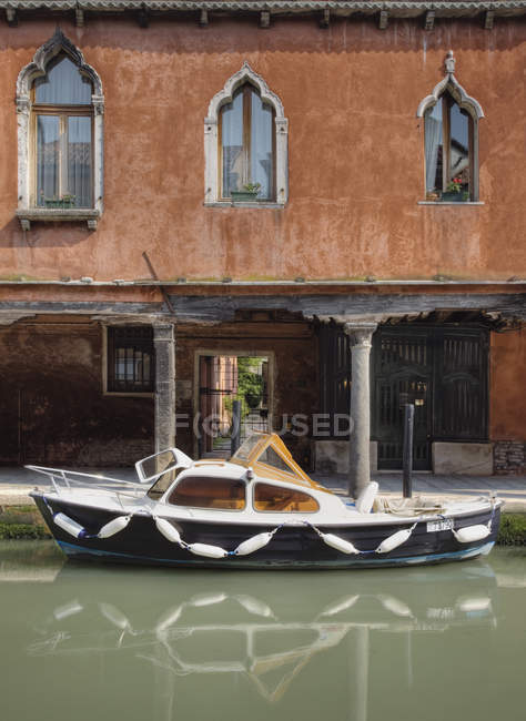 Barco amarrado por edificio antiguo en el canal en Venecia, Italia, Europa - foto de stock