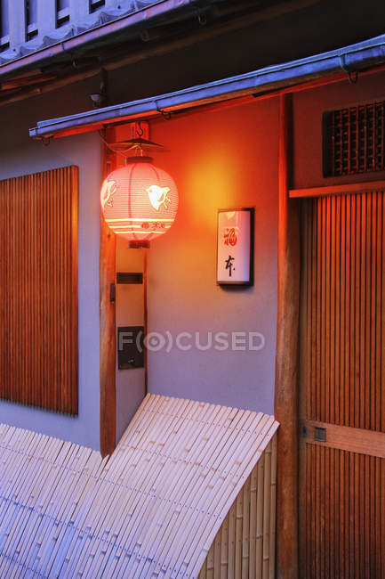 Traditional Japanese house with illuminating lantern and sign on wall, Kyoto, Japan — Stock Photo