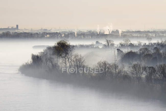 Niebla envuelta río y planta industrial en la distancia, Louisiana, EE.UU. - foto de stock