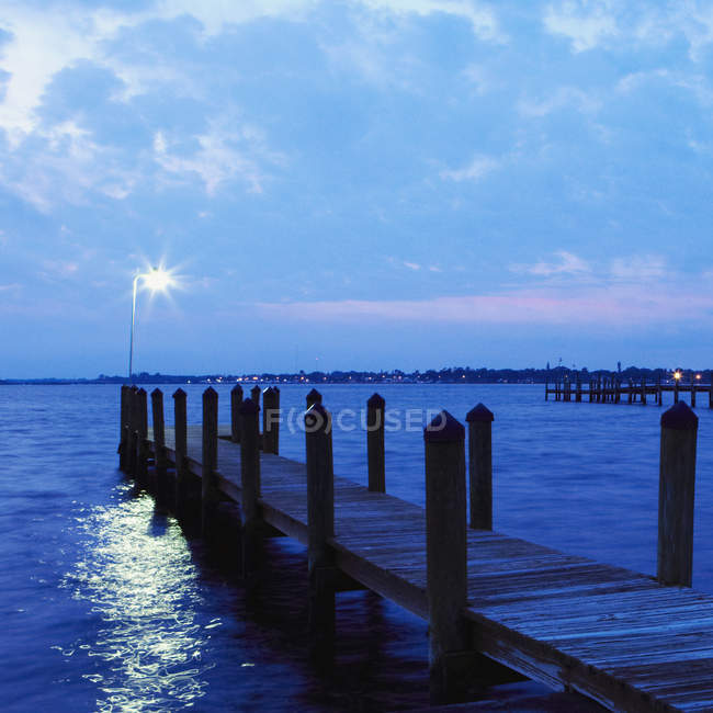 Lampada illuminata ai margini del molo sul lago al crepuscolo, Contea di Manatee, Stati Uniti — Foto stock
