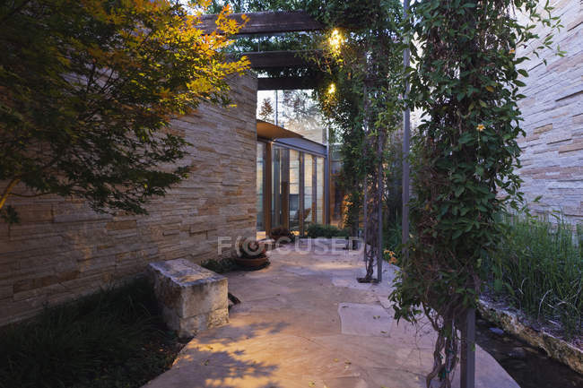 Casa di lusso ingresso nel crepuscolo in una vegetazione lussureggiante — Foto stock