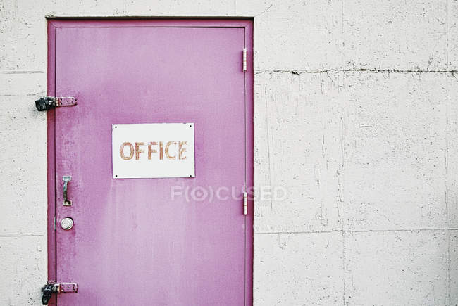 Office sign on locked door in pink on grey wall — Stock Photo