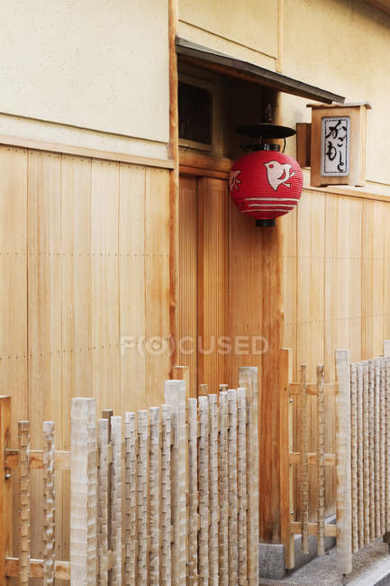 Lâmpada asiática vermelha pendurada fora da porta de construção em Kyoto, Japão — Fotografia de Stock