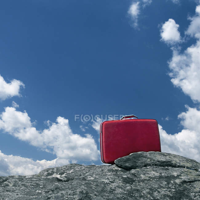 Самотня червона валіза на каменях на відкритому повітрі — стокове фото