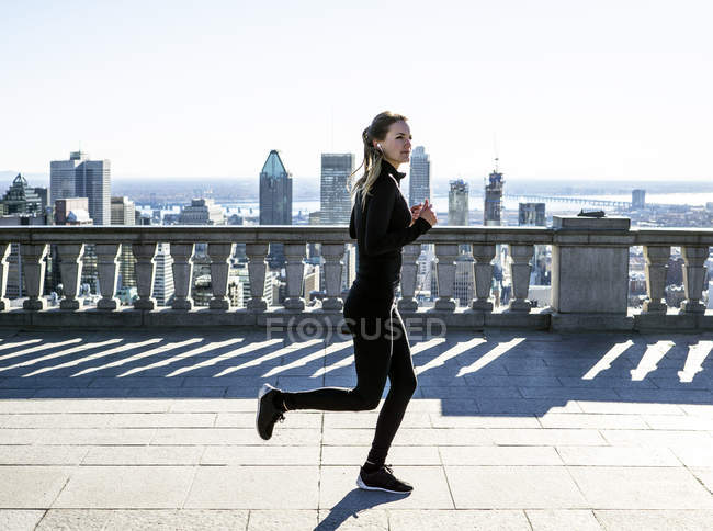 Donna caucasica che corre in città con grattacieli in lontananza, Montreal, Canada — Foto stock