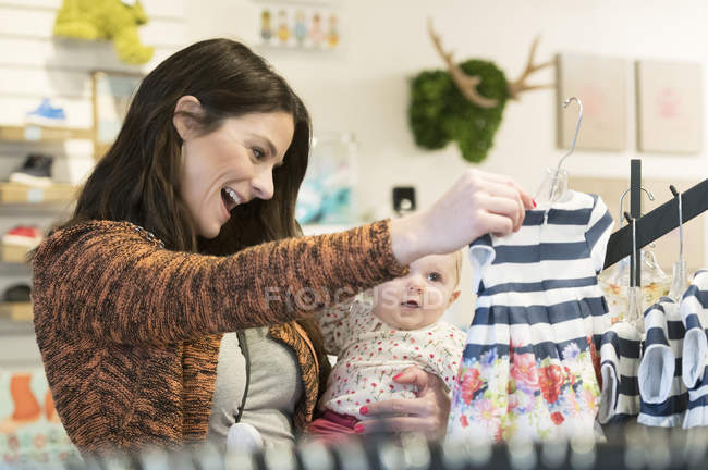 Caucasian mother and baby daughter shopping in clothing store — Stock Photo
