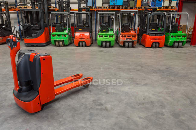 Mechanical dolly and forklift machinery in warehouse — Stock Photo
