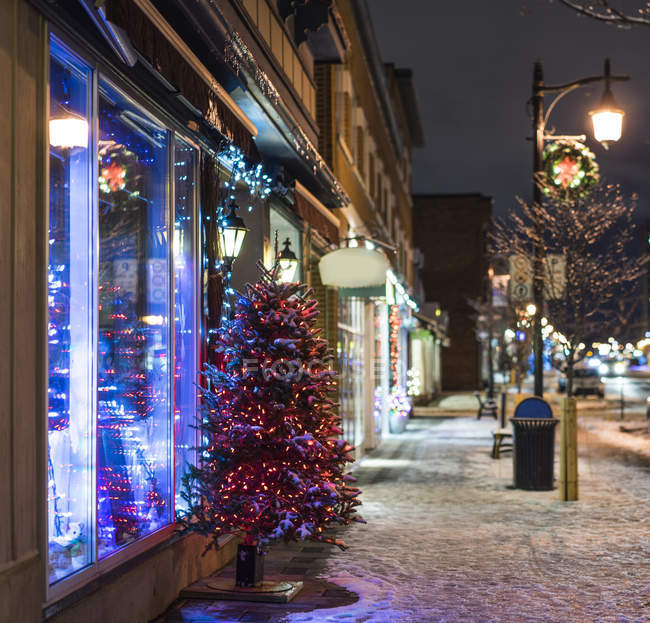 Snow and Christmas tree on city sidewalk at night, Montreal, Canada — Stock Photo