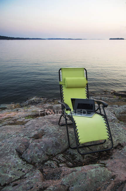 Ноутбук на стільці на галявині біля віддалених річок, Канада — стокове фото