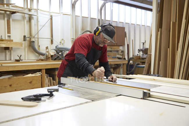 Carpintero con sierra de mesa en el interior del taller . - foto de stock