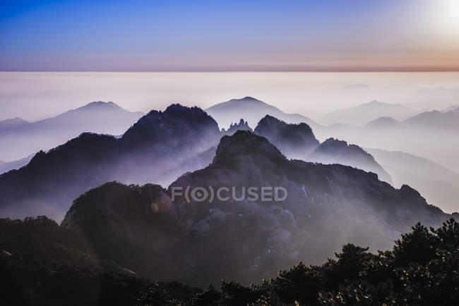Nevoeiro rolando sobre montanhas rochosas, Huangshan, Anhui, China — Fotografia de Stock