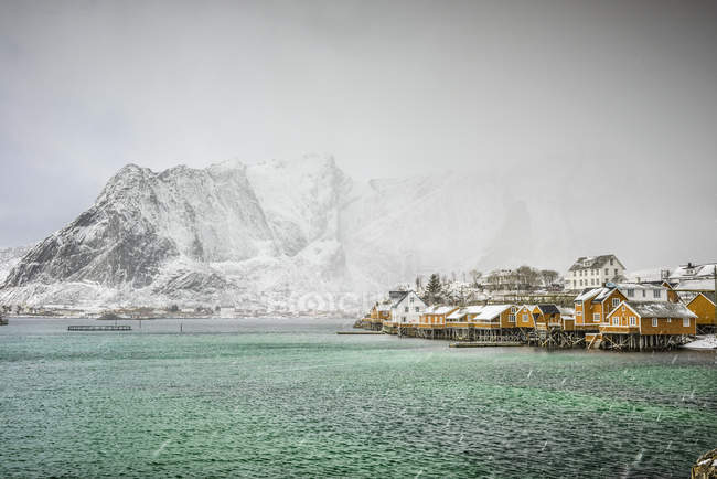 Snowy mountains overlooking rocky coastline, Reine, Lofoten Islands, Norway — Stock Photo