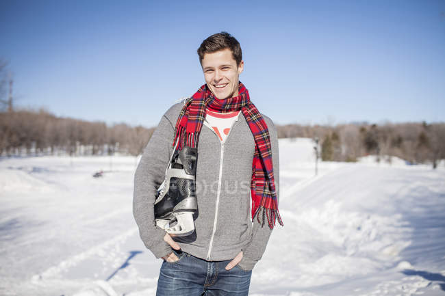 Uomo caucasico che trasporta pattini da ghiaccio nel parco invernale — Foto stock